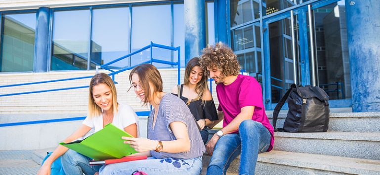 Group of students studying together on campus steps, representing student life at the best colleges in London.