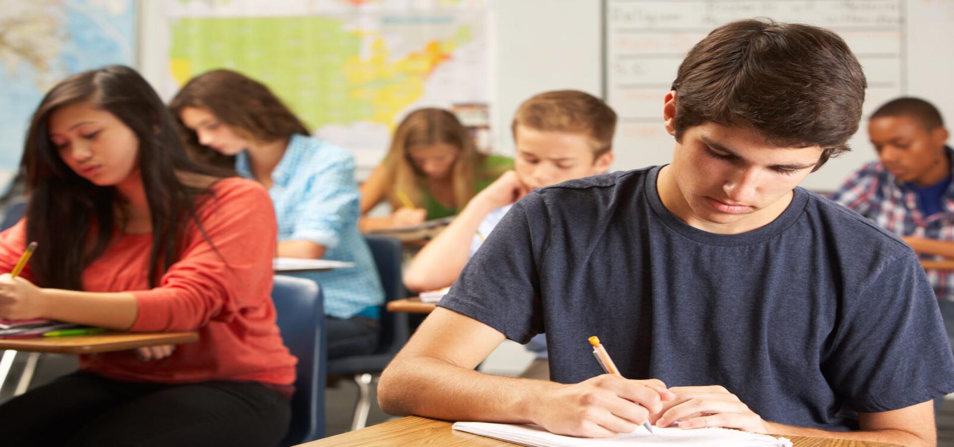Students focused on writing during a class, representing academic work and learning in higher education.