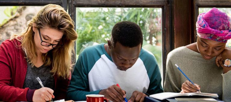Three students focused on studying together, representing academic life at colleges in East London.