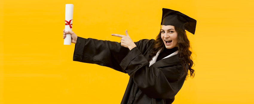 Happy graduate in cap and gown pointing at diploma, celebrating completion of HND and Diploma courses.