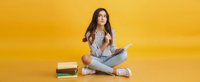 Thoughtful student sitting with books and notebook, representing planning for a BTEC Higher National Diploma.