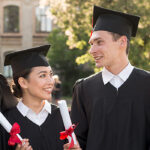 Four graduates in black caps and gowns holding diplomas, celebrating outdoors, representing the History and Evolution of HND courses achievements.