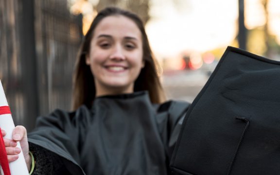 Smiling graduate holding a diploma and cap, symbolizing HND levels and frameworks in different countries.