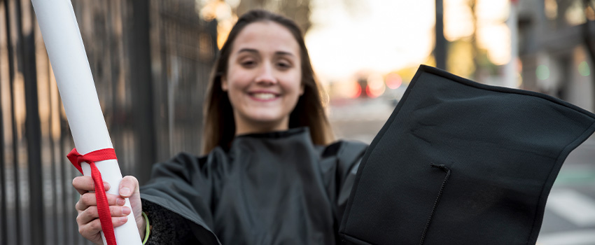 Smiling graduate holding a diploma and cap, symbolizing HND levels and frameworks in different countries.