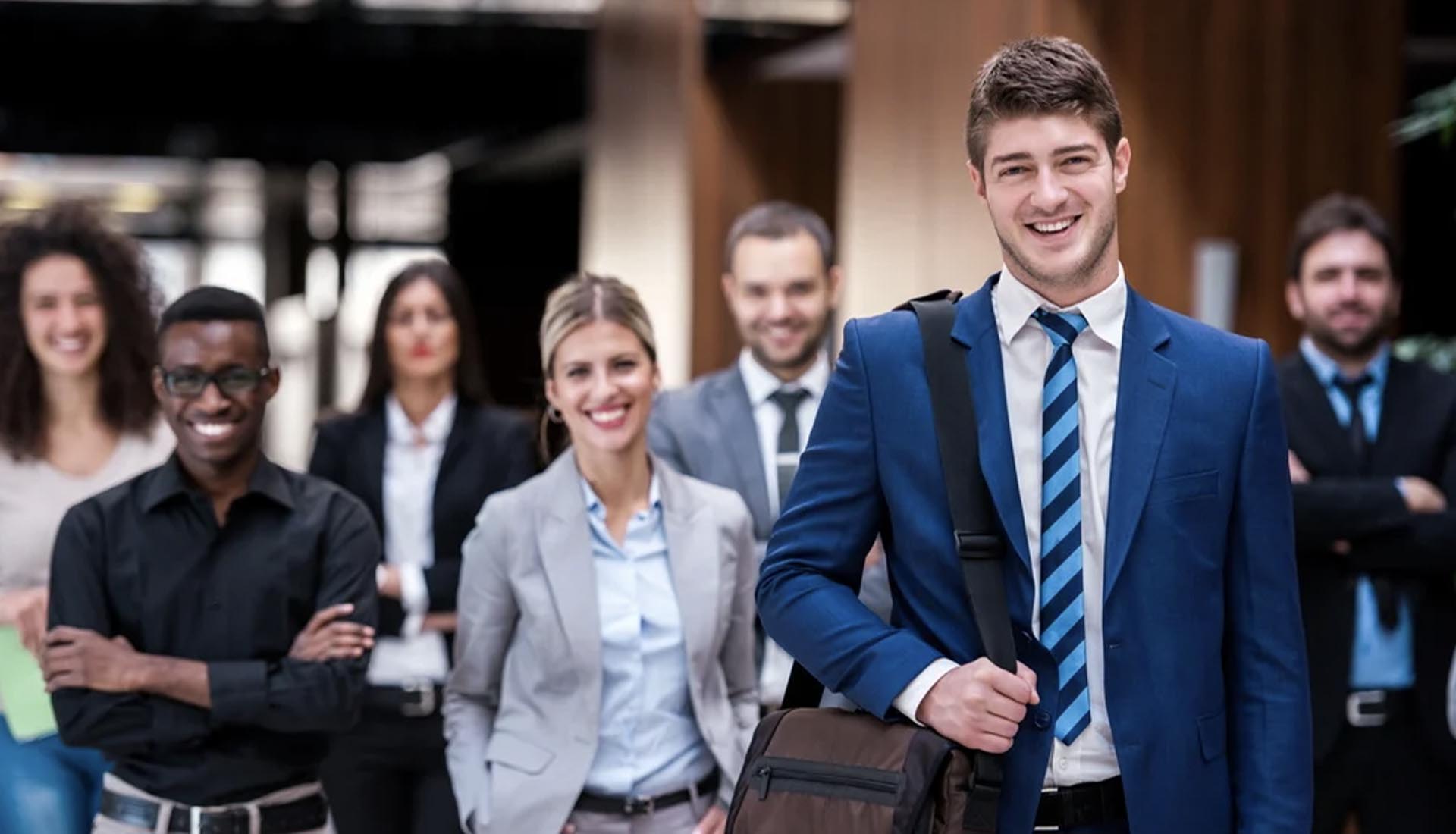 A confident young professional in a blue suit leads a diverse team, showcasing HND and career pathways success.