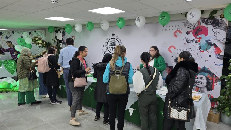 Attendees gather at Mont Rose College Macmillan Charity Event, decorated with green balloons and themed banners.