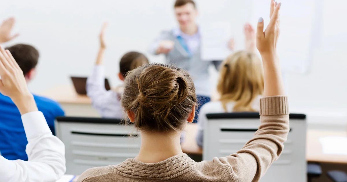 Students raising hands during classroom session, engaging in discussion. Focus on How HNDs Are Assessed.