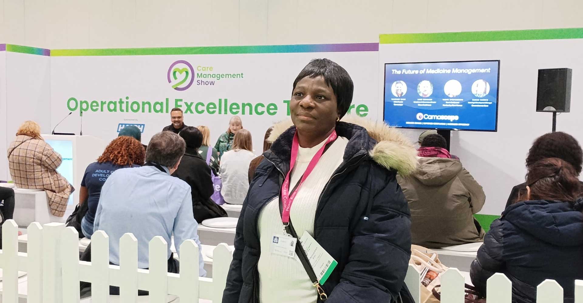 Woman attending the Care Management Show, standing near the Operational Excellence Theatre during a session on the Future of Medicine Management.