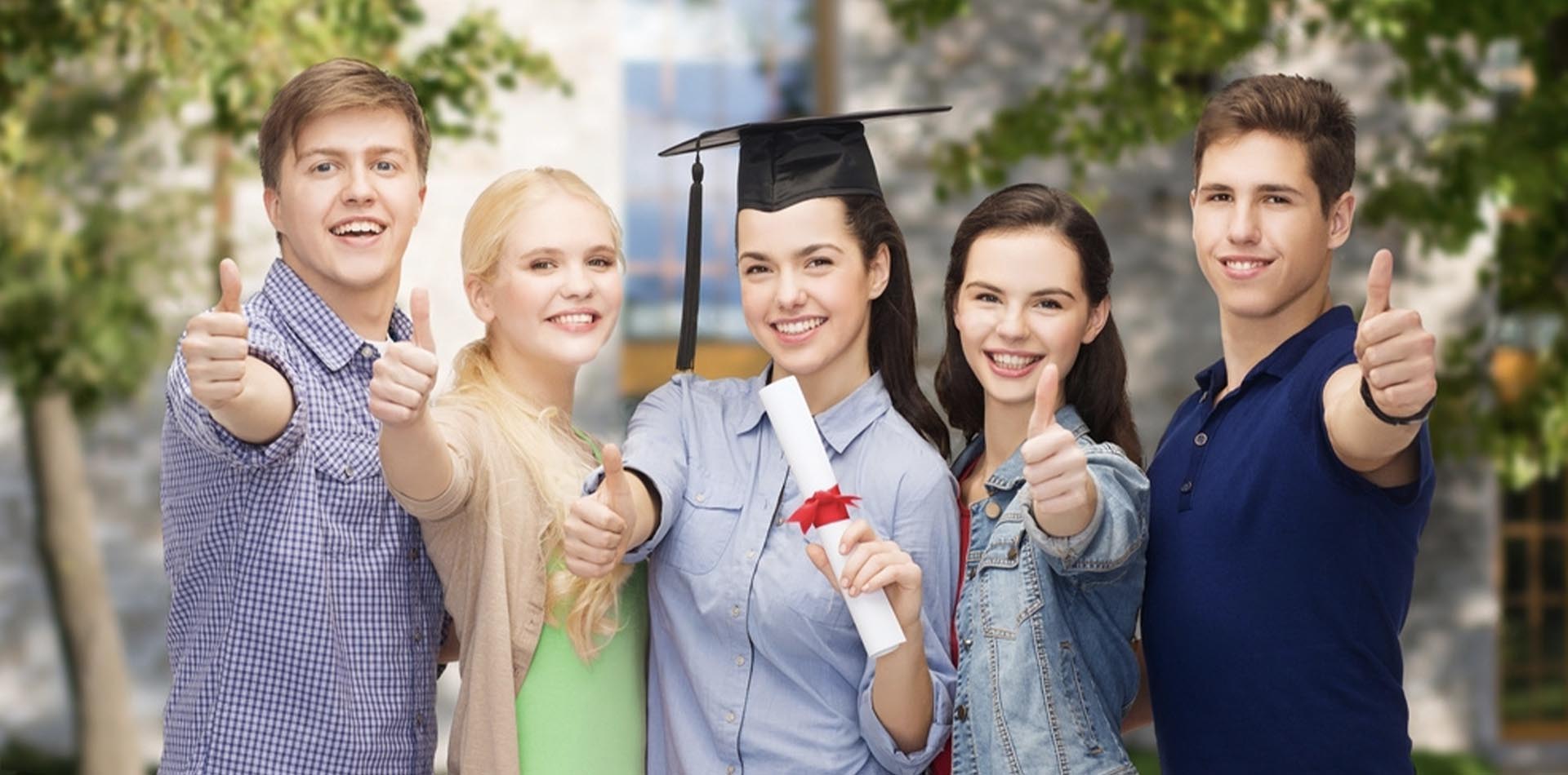 Group of smiling students celebrating graduation, holding a diploma, and showing thumbs up, highlighting the Importance of Accreditation for HNDs, set against a green outdoor background