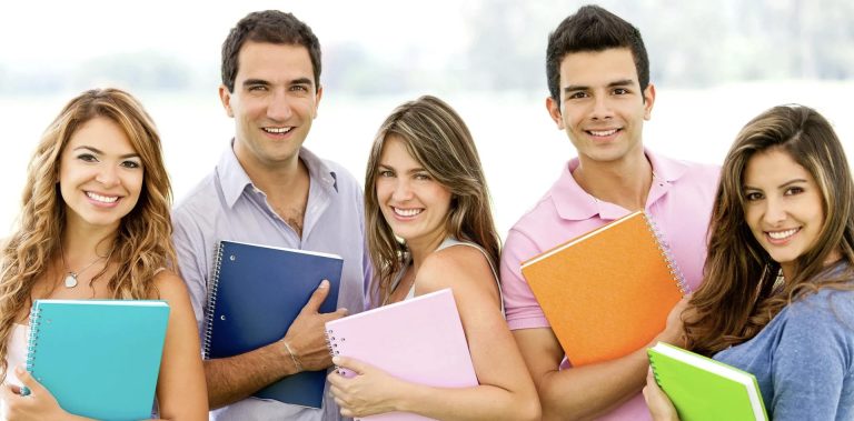 A diverse group of students smiling outdoors while holding colorful notebooks, symbolizing teamwork and success in the HND Program.