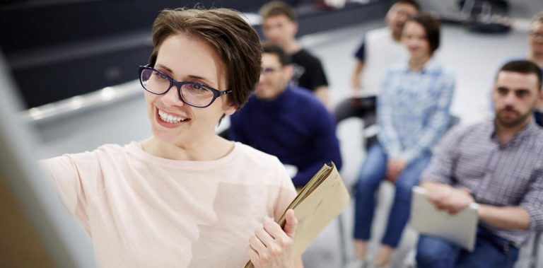 Smiling female lecturer explaining a concept to engaged students in a classroom setting, promoting active learning in HND Programs and professional education