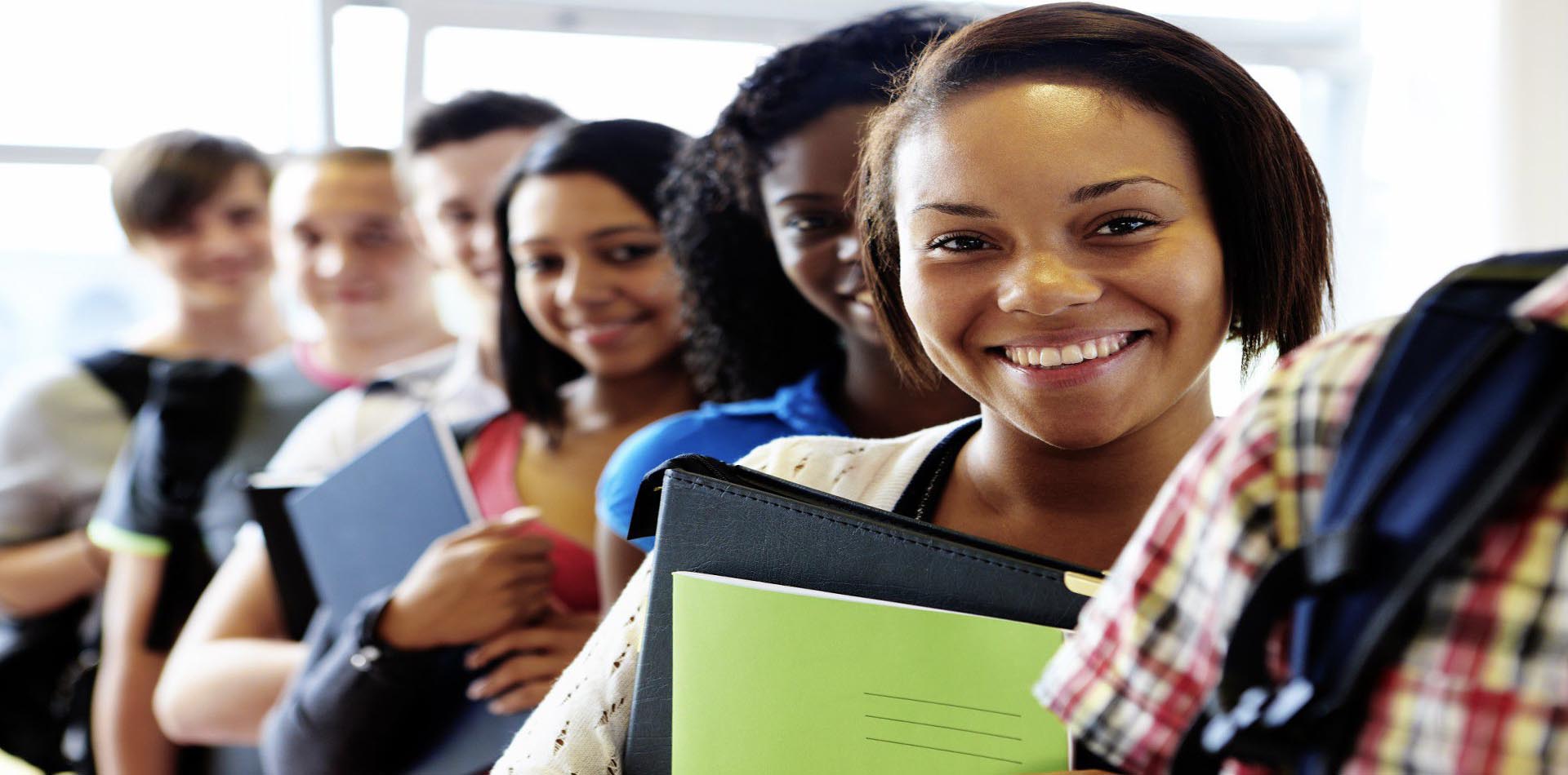 Smiling students standing in a queue, holding notebooks and backpacks, showcasing diversity and enthusiasm for academic excellence through HND Programs