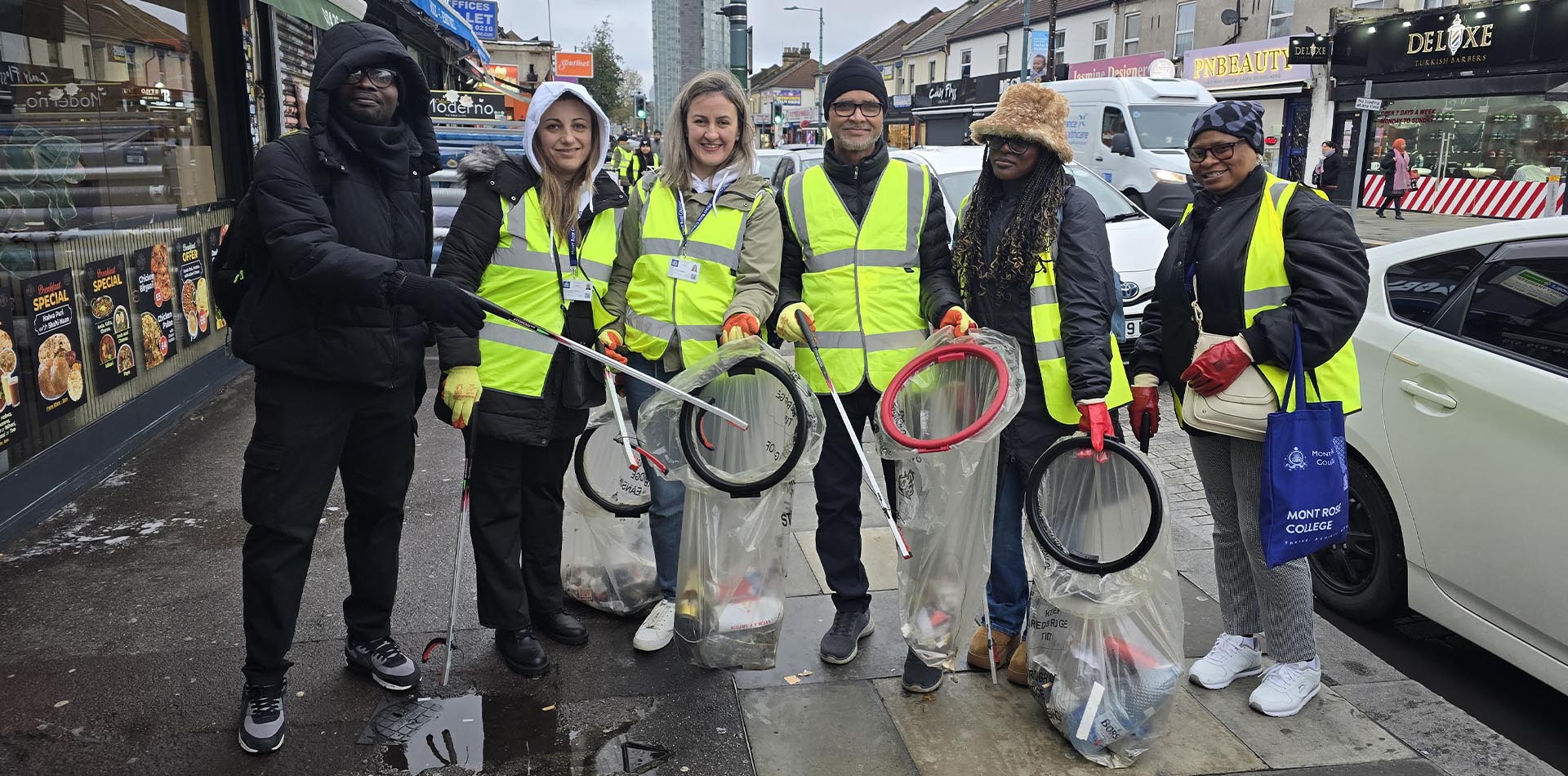 Volunteers in high-visibility vests hold litter pickers and bags filled with rubbish during a Greener Ilford Lane litter-picking initiative