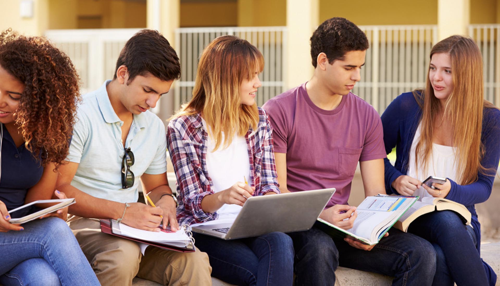 a-group-of-students-studying-together-outdoors-with-books-and-a-laptop-highlighting-the-benefits-of-hnd-qualifications-for-academic-growth