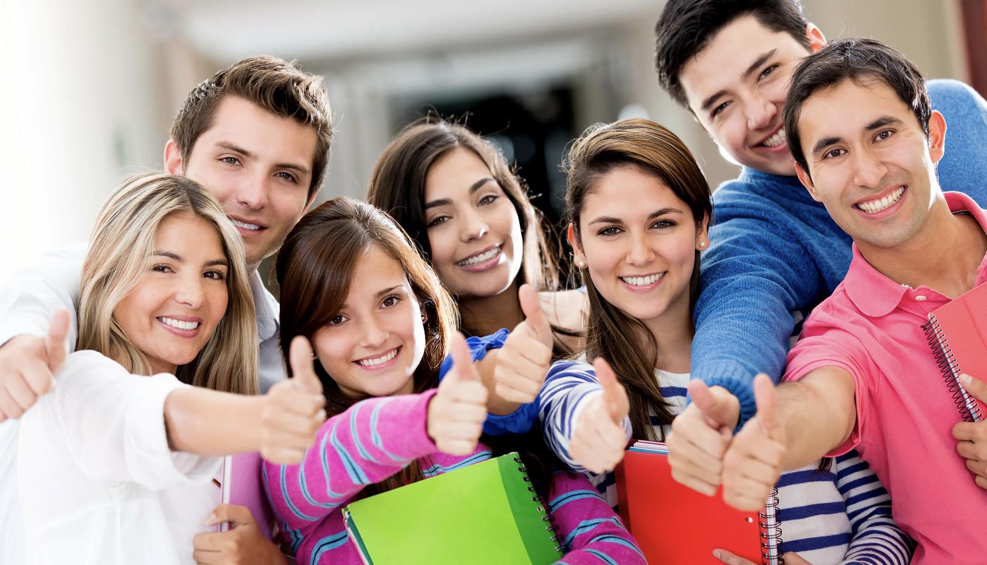A group of happy students giving thumbs up while holding notebooks, symbolizing success in an HND Course.