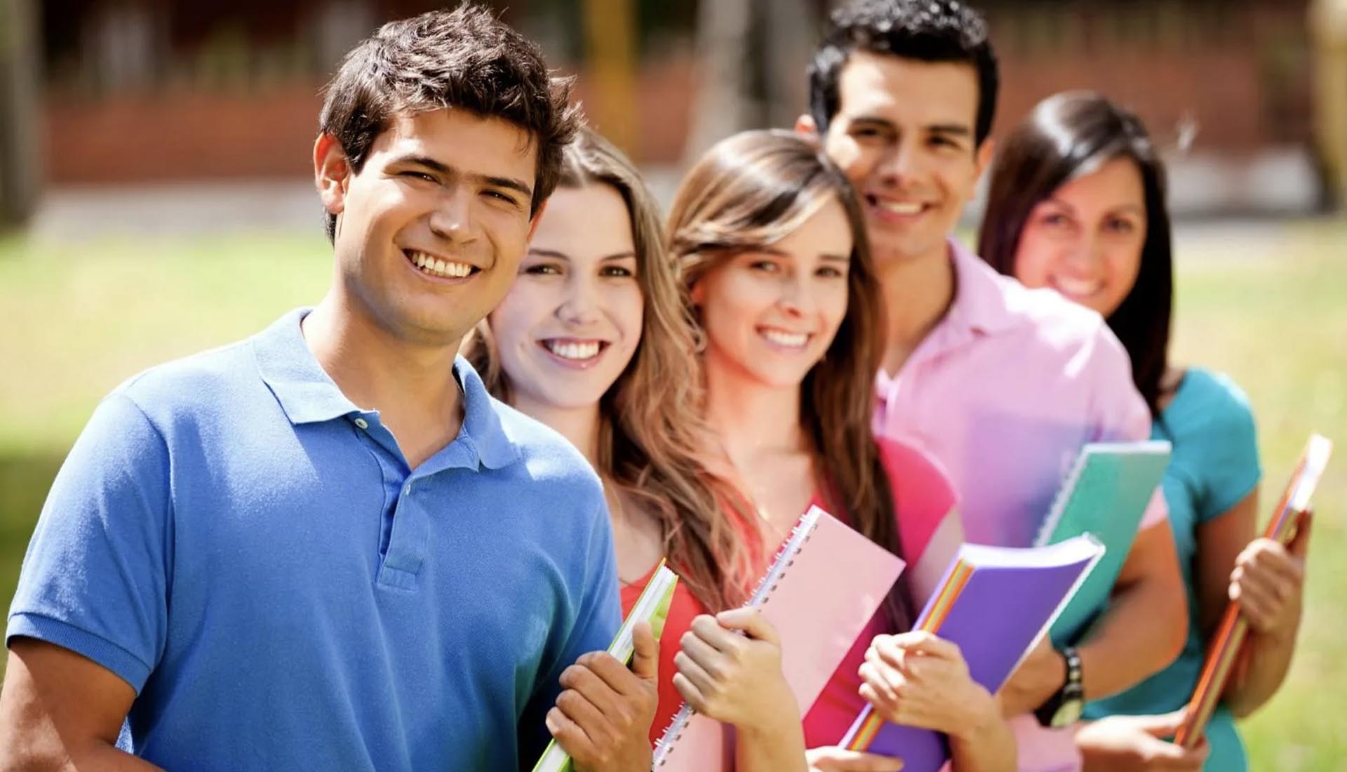 A group of happy students holding notebooks and smiling outdoors, representing success in their HND Course journey.