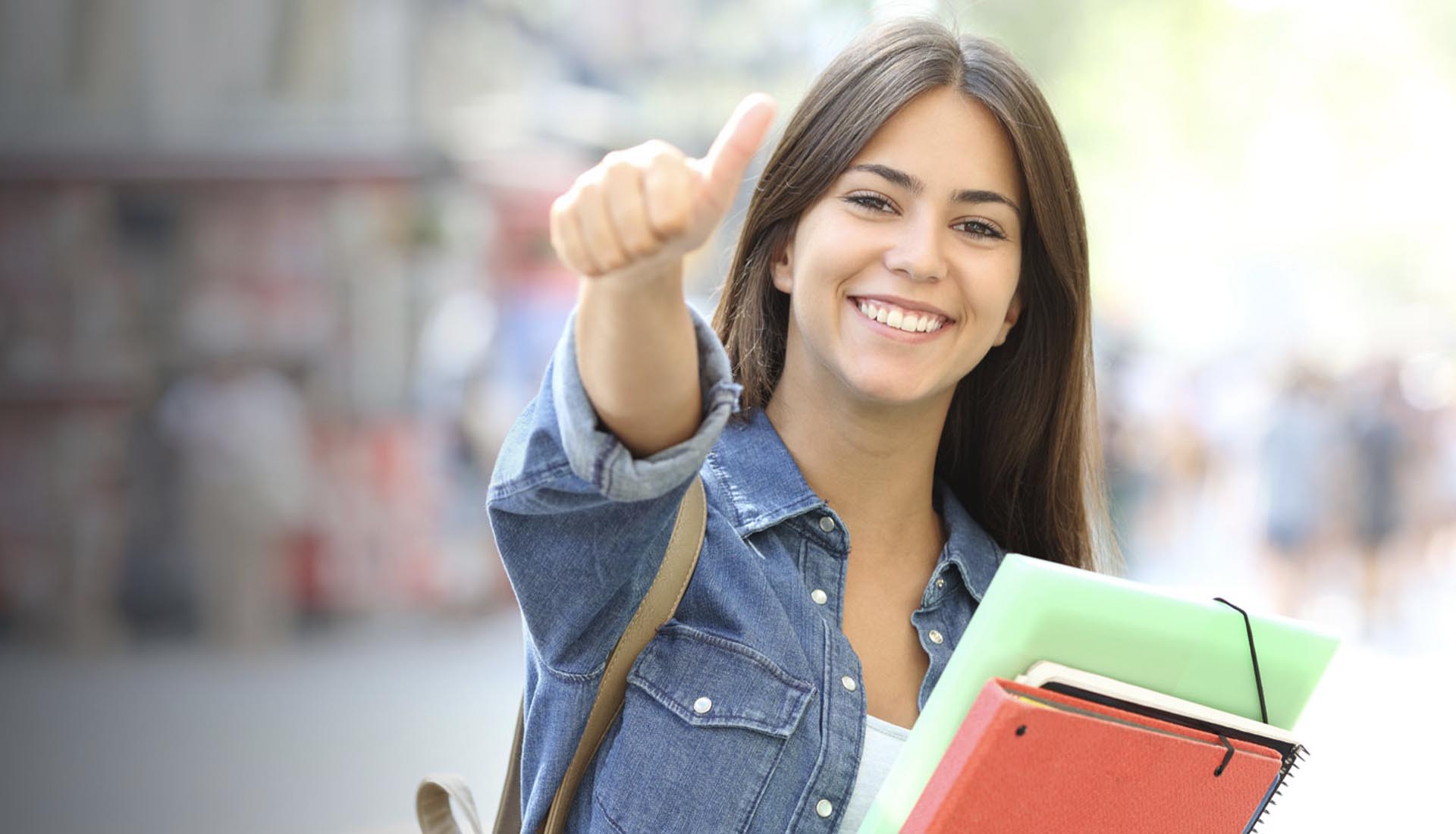 A happy student holding notebooks gives a thumbs-up, representing the Affordability of HND Courses and accessible education.