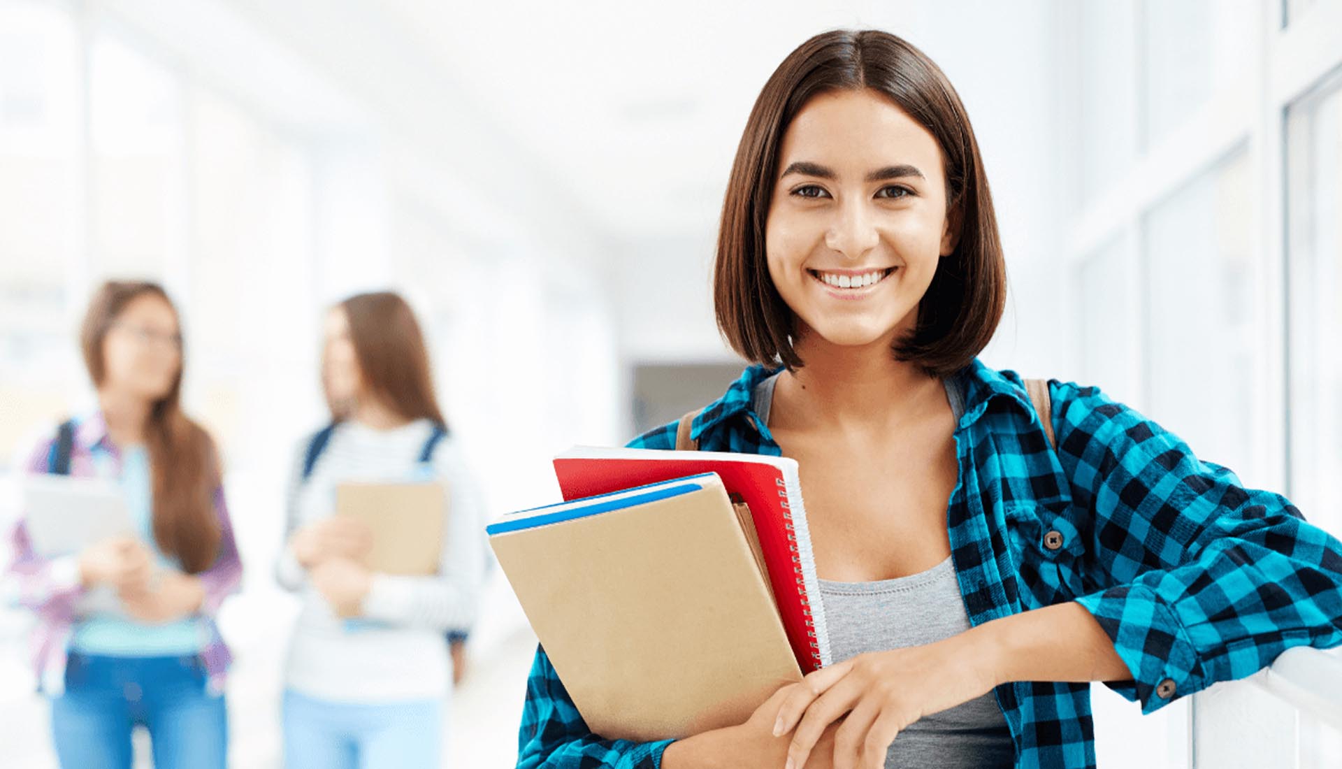 Smiling student holding books, representing the value of HND Qualifications for academic and career advancement.