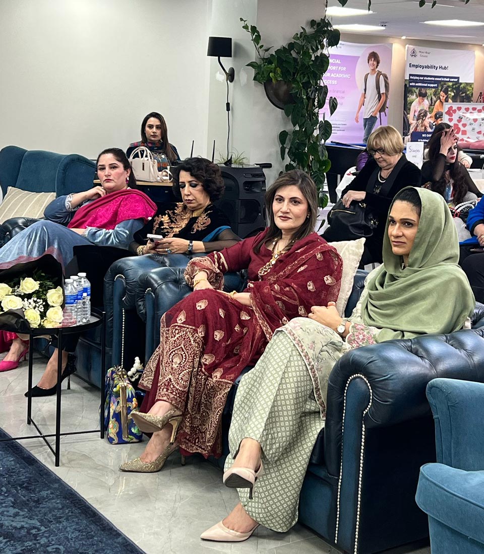 Women in elegant traditional attire attend Celebrating International Women's Day at Mont Rose College, engaging in discussions and appreciation.
