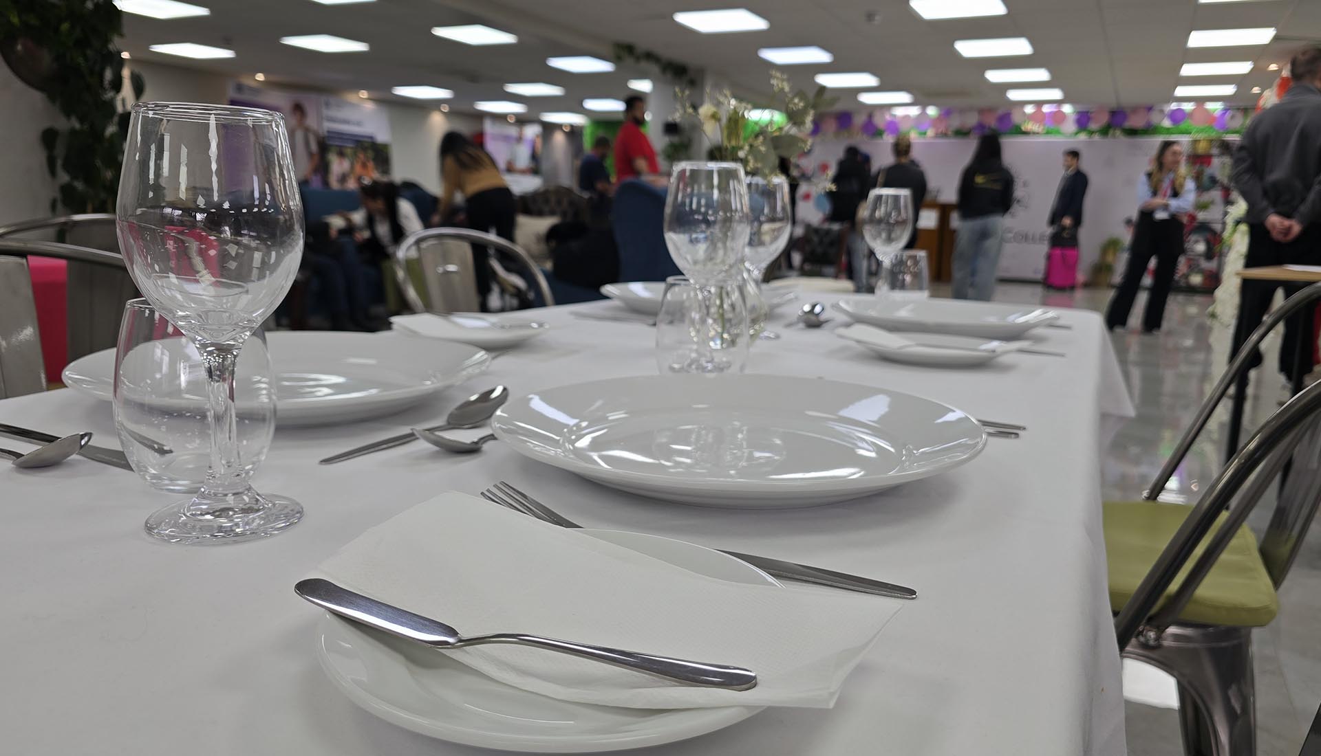 Close-up of a neatly set dining table with plates and glassware during a Hospitality Practical Workshop at Mont Rose College.