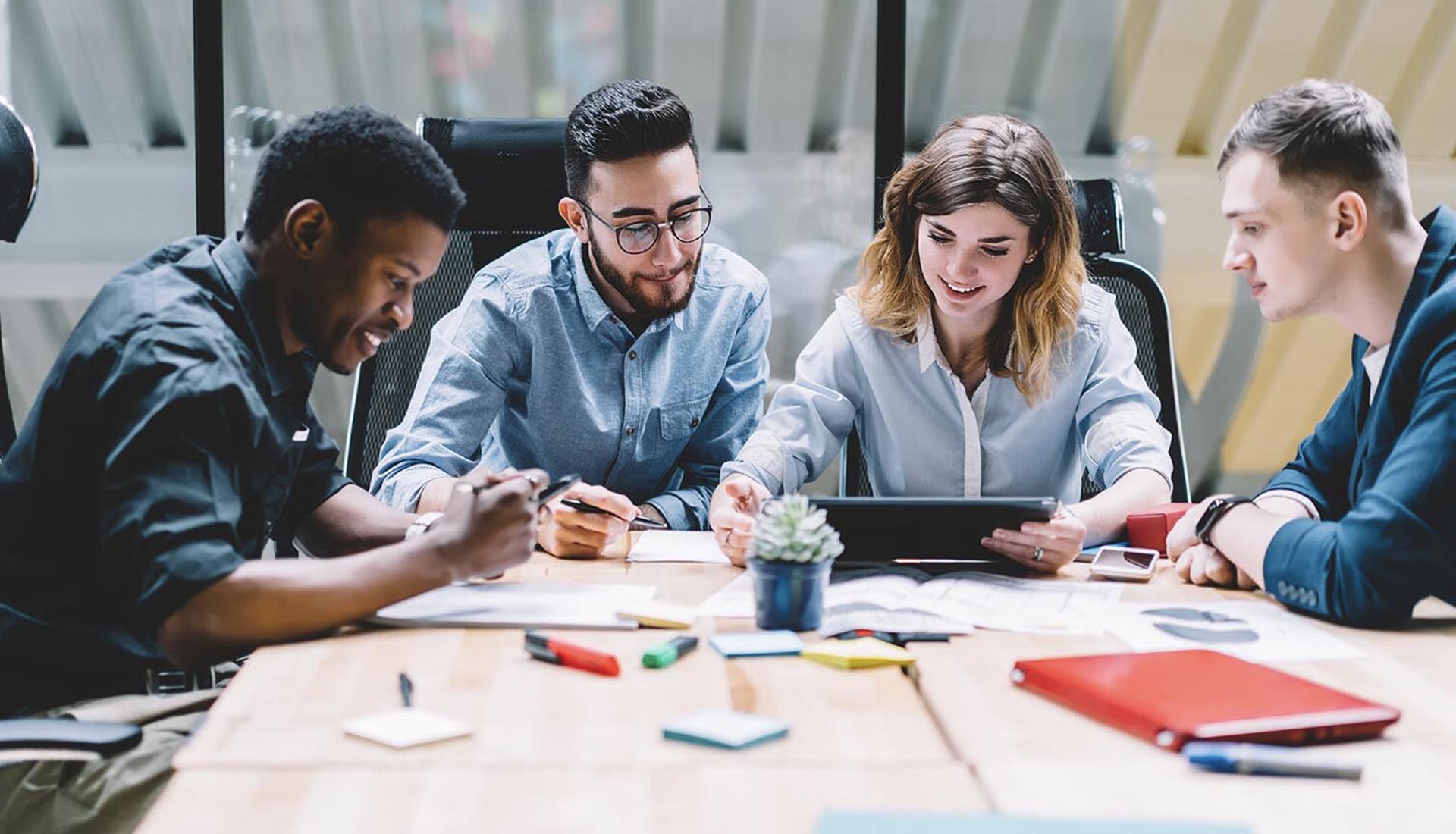 Group of students collaborating around a tablet and documents, representing Networking in an HND Programme.