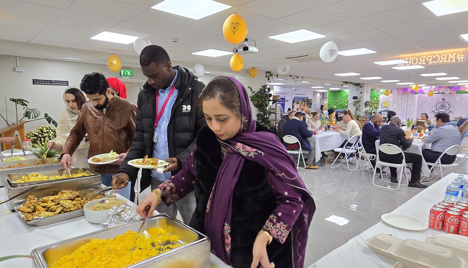 Guests serving themselves delicious food at the Iftar Dinner at Mont Rose College, celebrating together in a warm, festive setting.