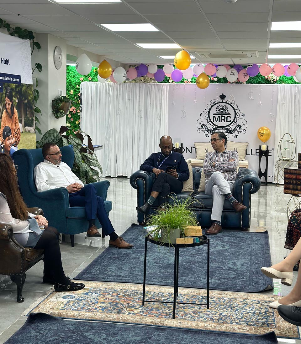 People engaged in a discussion at Mont Rose College's World Book Day event, surrounded by books and decorations.