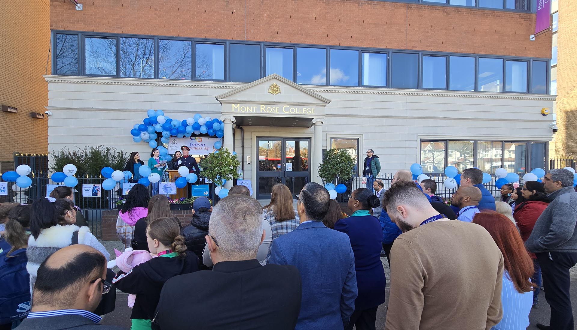 Crowd gathers outside Mont Rose College for a blue balloon-decorated stage at the Inspiring Autism Awareness Event.
