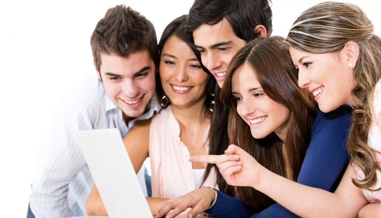 Group of happy students gathered around a laptop, highlighting affordability and return on investment for HND students.