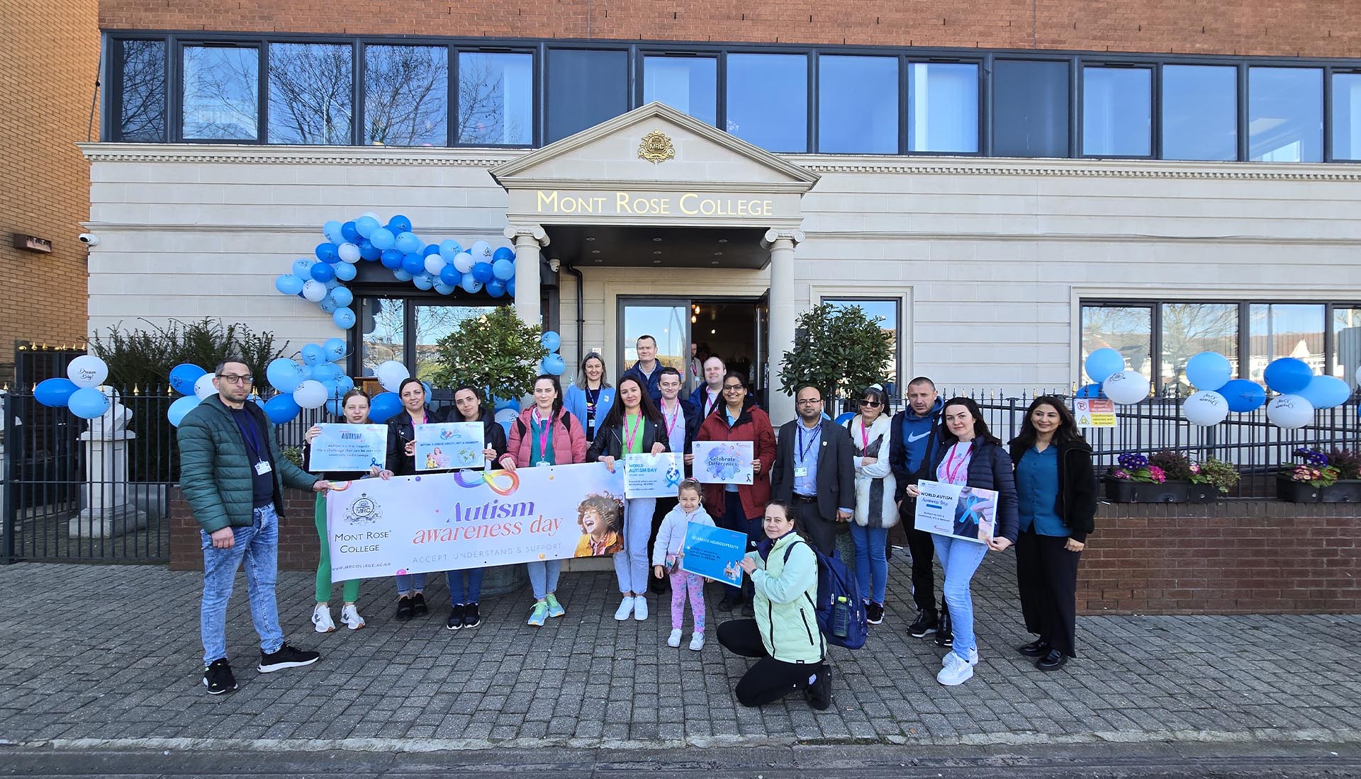 Group of people holding Autism Awareness signs outside Mont Rose College during the Inspiring Autism Awareness Event.