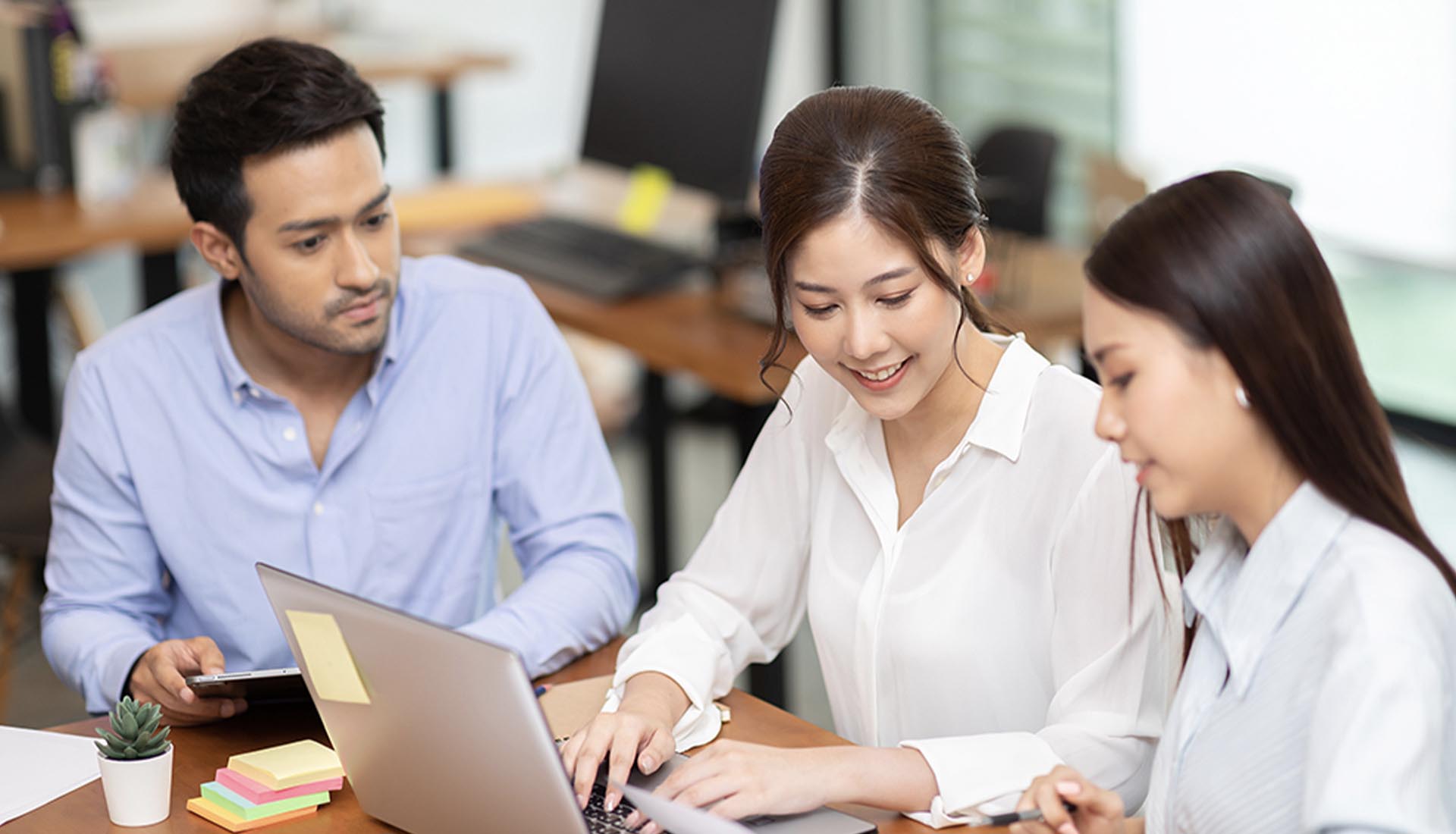 Three students working together on a laptop, showcasing industry relevant curriculum in HND courses.