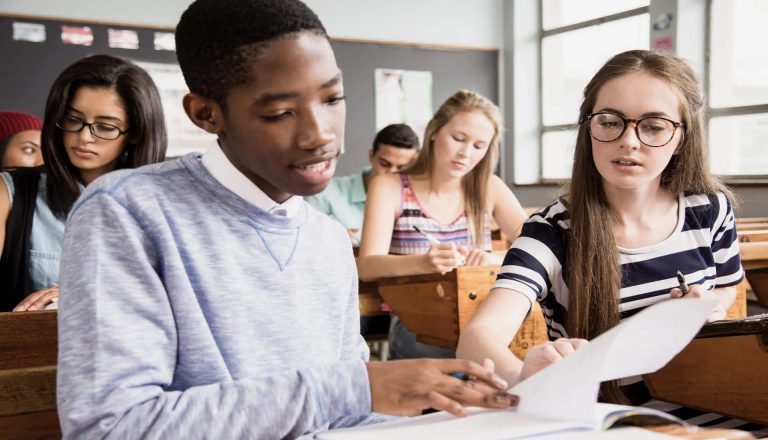Students discussing notes in a classroom setting, symbolizing the comparison between HND vs Apprenticeships educational paths.