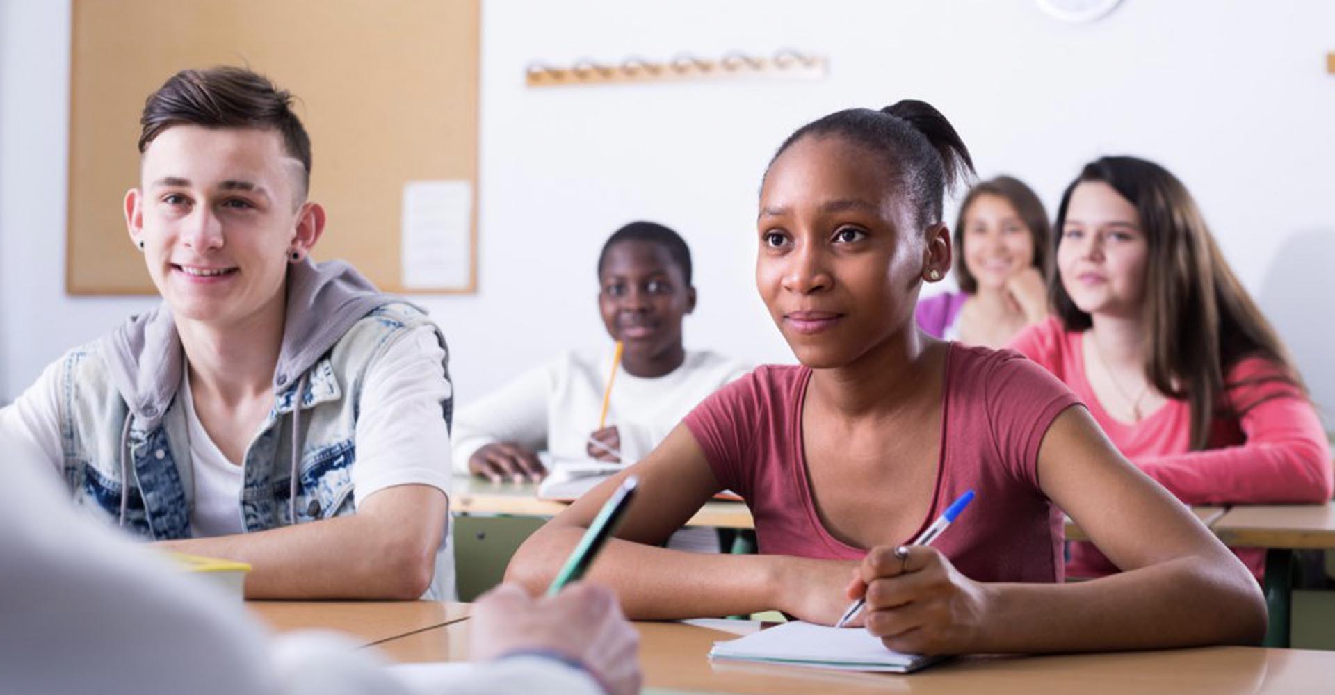 Engaged students taking notes in a classroom, representing academic focus on HND vs Foundation Degrees pathways.