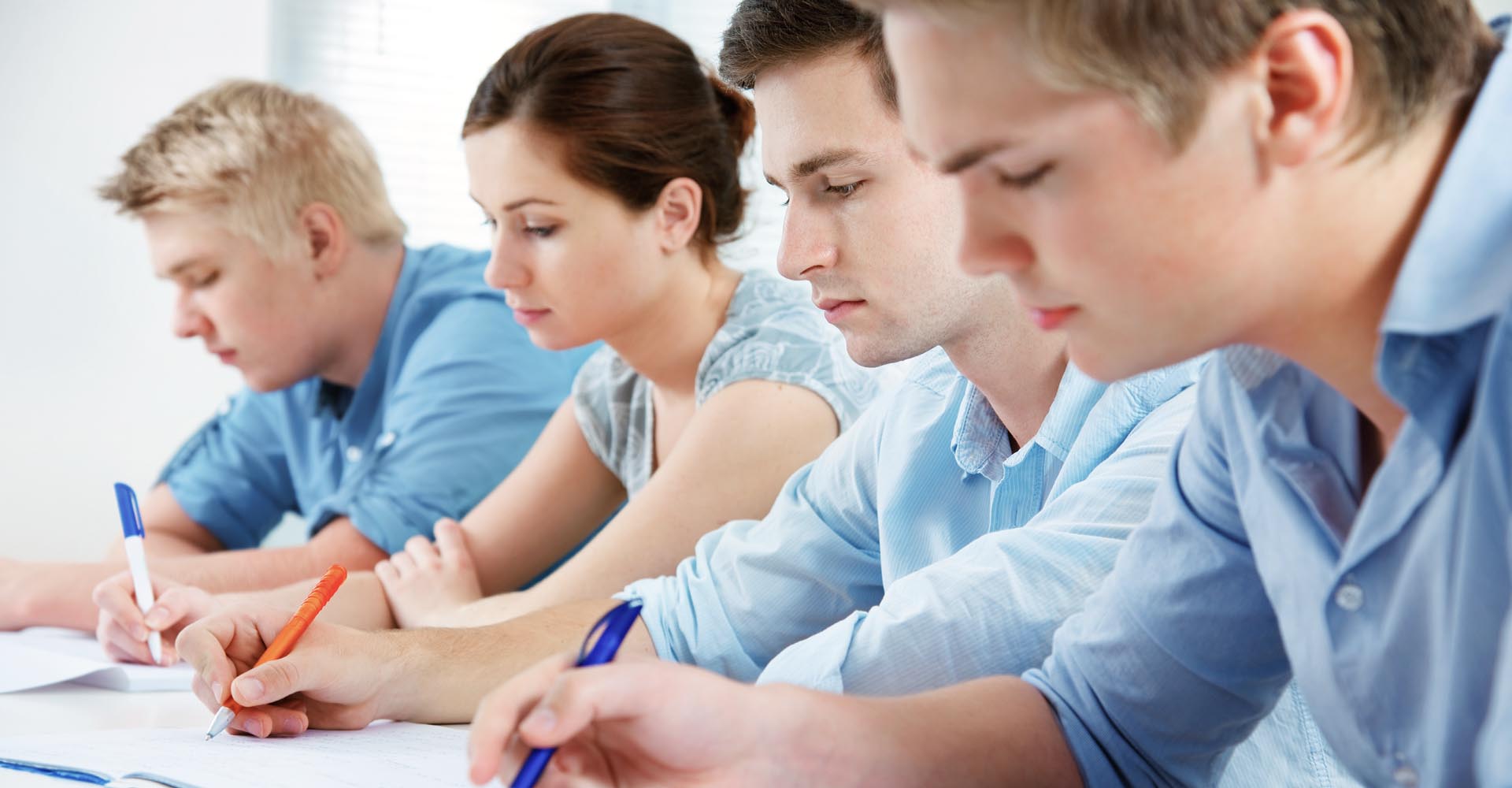Focused students writing in a classroom, representing commitment to education through HND and distance learning programs.