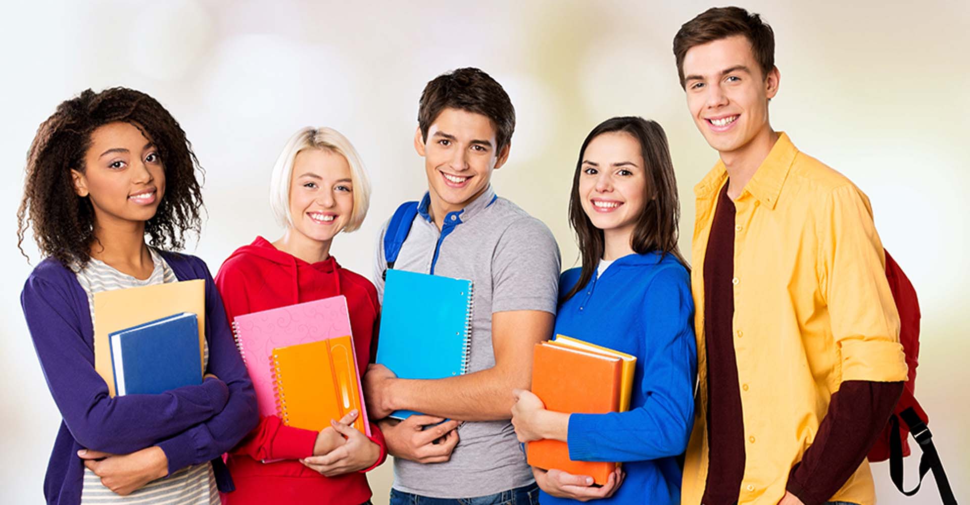 Group of smiling students holding notebooks, symbolizing educational choices like HND vs Associate Degrees.