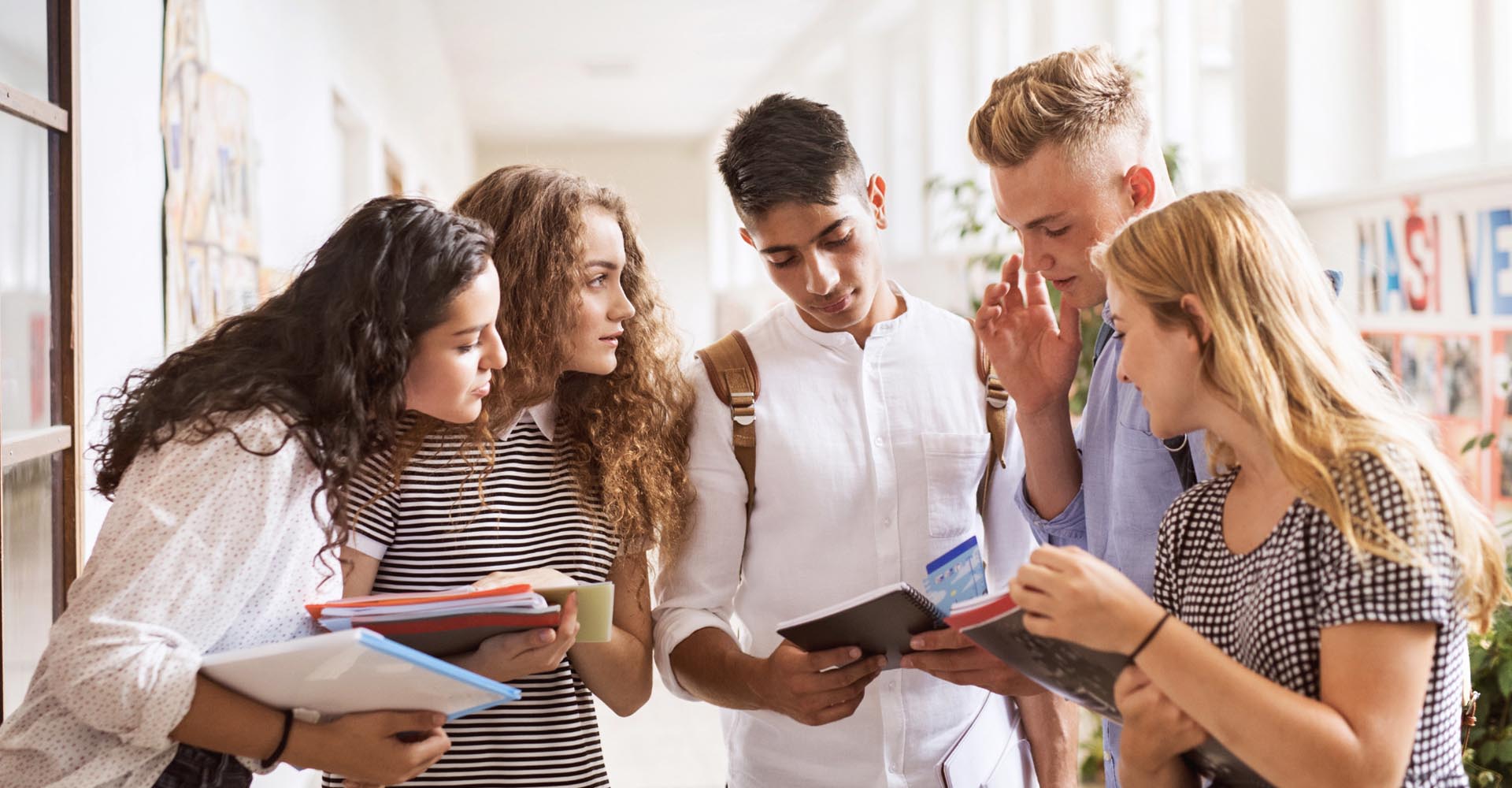 Group of students discussing notes in a hallway, representing academic choices like HND vs bachelor’s degree.