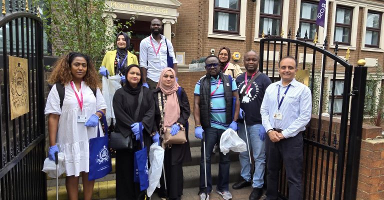 Group of volunteers with gloves and litter pickers outside Mont Rose College, participating in an Environment Day cleanup event.