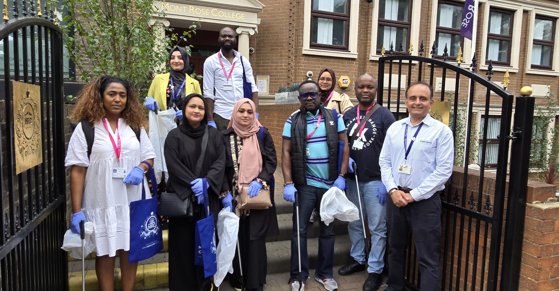 Group of volunteers with gloves and litter pickers outside Mont Rose College, participating in an Environment Day cleanup event.