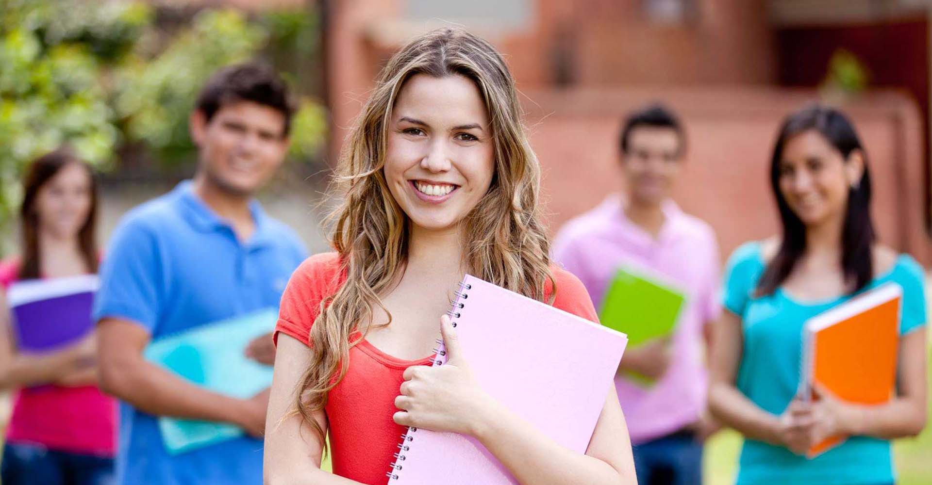 Smiling student holding a pink notebook outdoors, symbolizing educational choices like HND vs Diplomas.