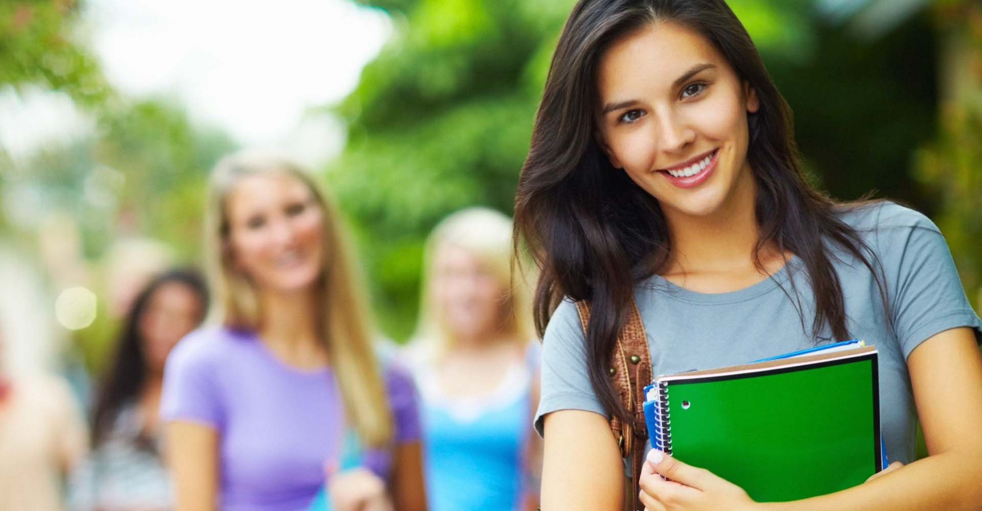Smiling student holding notebooks on campus, representing educational choices like HND vs Online Certifications.
