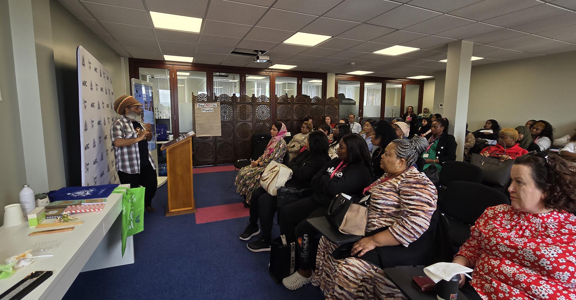 Speaker addressing a full audience at Mont Rose College during an Environment Day event focused on reducing plastic use.