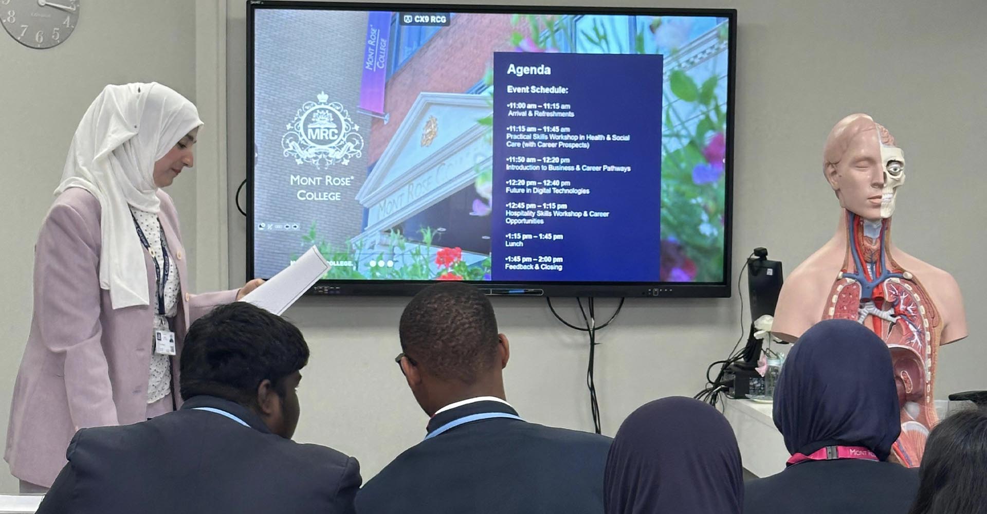 Students from Cumberland High School attend a career workshop at Mont Rose College, viewing an agenda on screen.