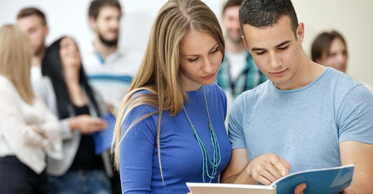 Two students reviewing a notebook together, representing a comparison of HND vs Distance Learning Programs.