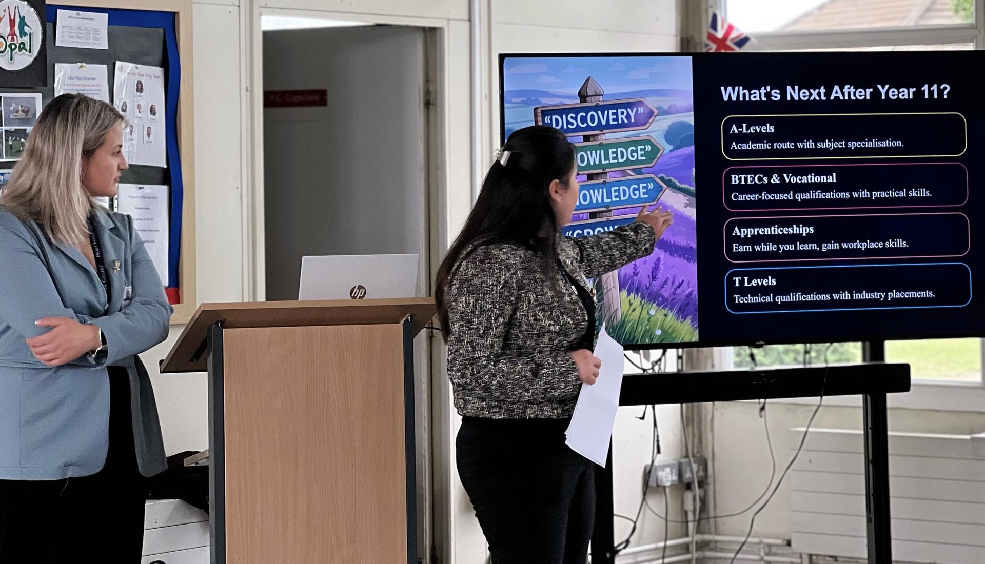 Two women presenting post-Year 11 pathways slide, discussing Higher Education options including A-Levels, BTECs, and T Levels.