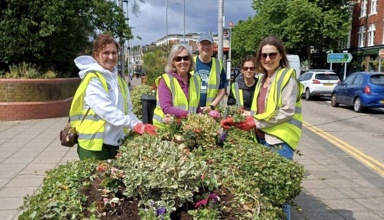 Volunteers planting flowers on a city street, supporting the Greener Redbridge community environmental initiative.