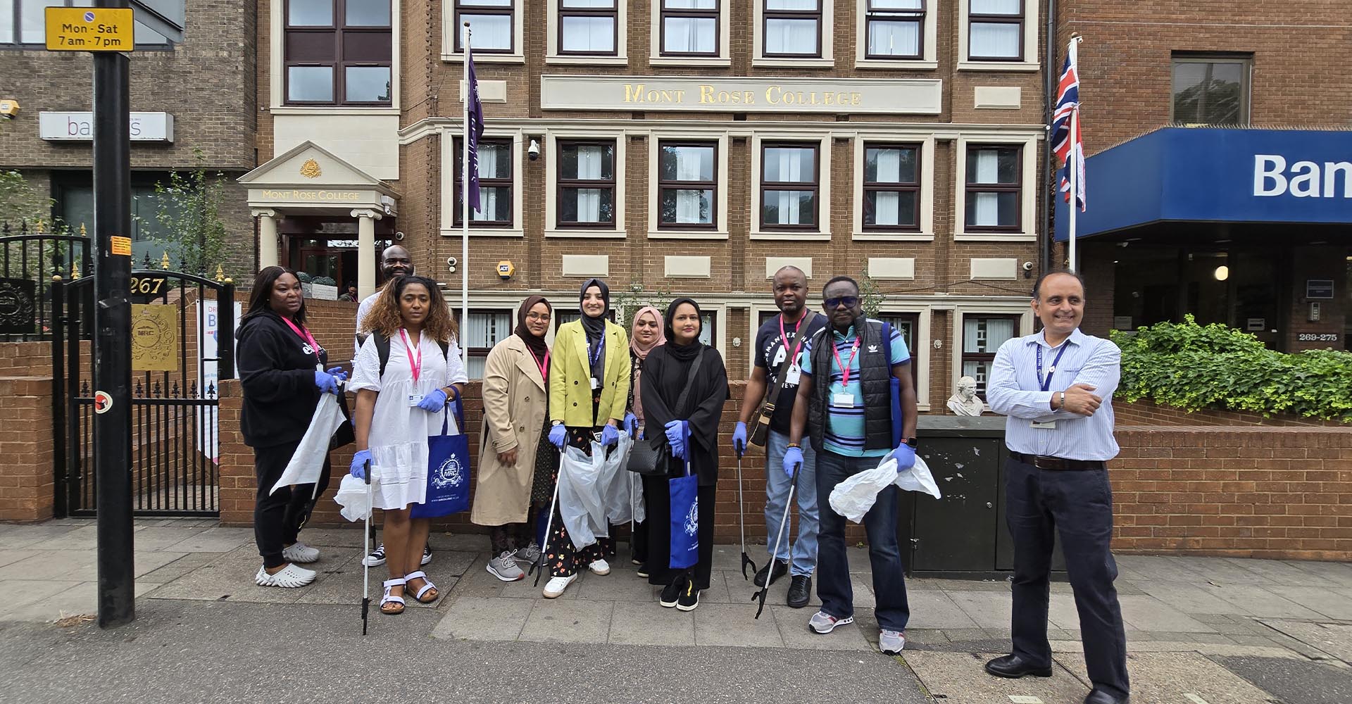 Volunteers with gloves and litter pickers posing outside Mont Rose College for a community cleanup on Environment Day.