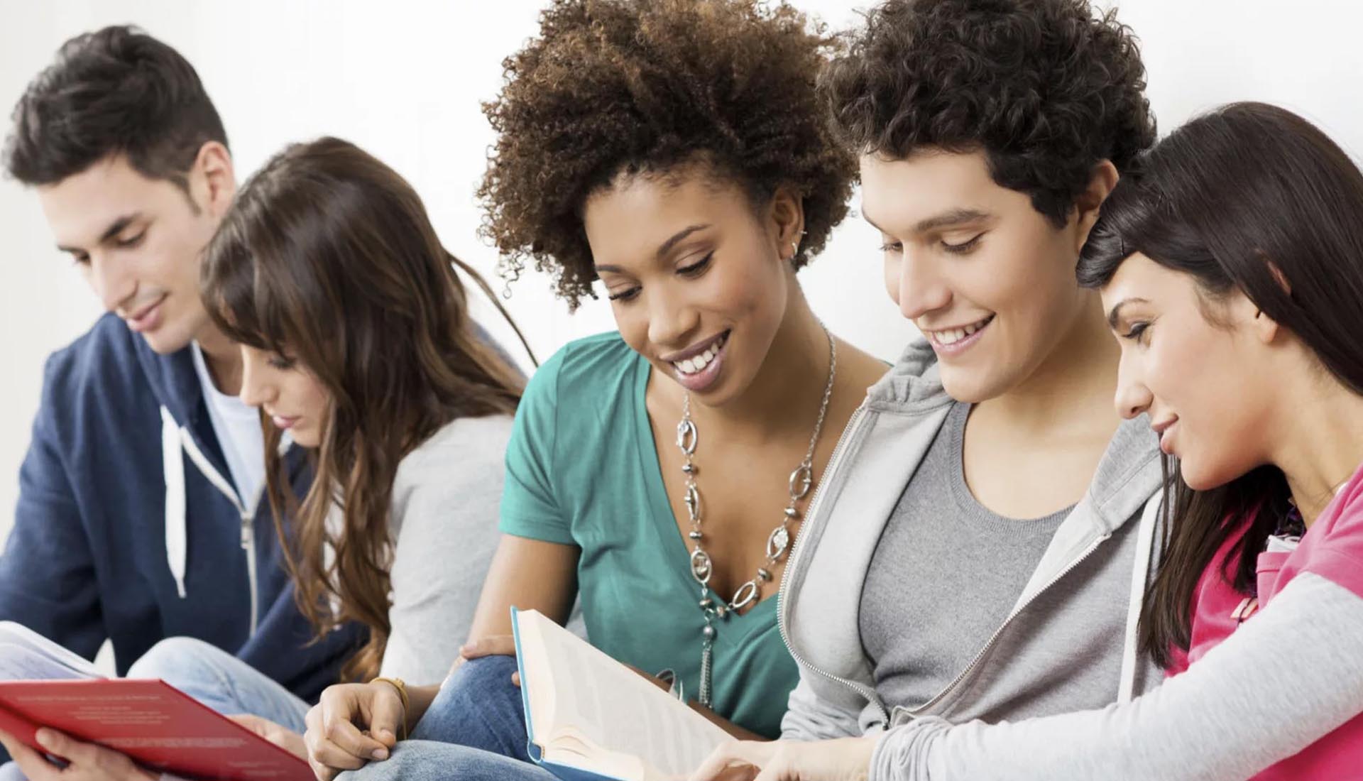 Group of students reading together and smiling, reflecting collaborative learning in HND and Part-Time Degree programs.