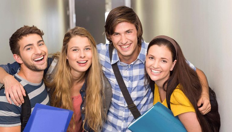 Smiling group of students holding folders, representing academic learning in contrast to HND vs On-the-Job Training options.