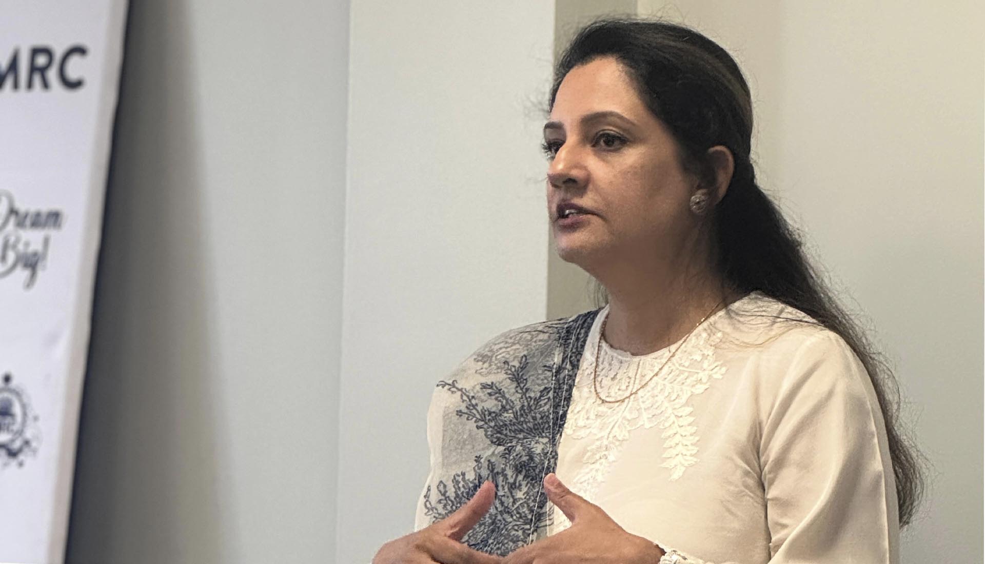 Speaker presenting on the topic of AI in healthcare, standing in front of a Mont Rose College banner during a seminar.