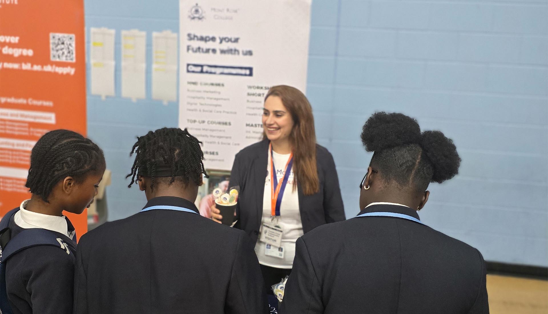 Students interacting with a representative at the Mont Rose College career fair booth, exploring educational programs and opportunities.